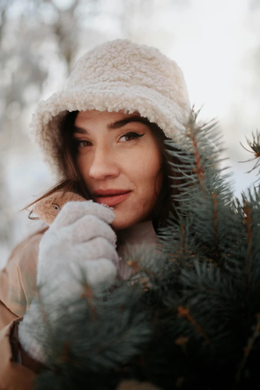 woman standing in snowy woods with a christmas tree