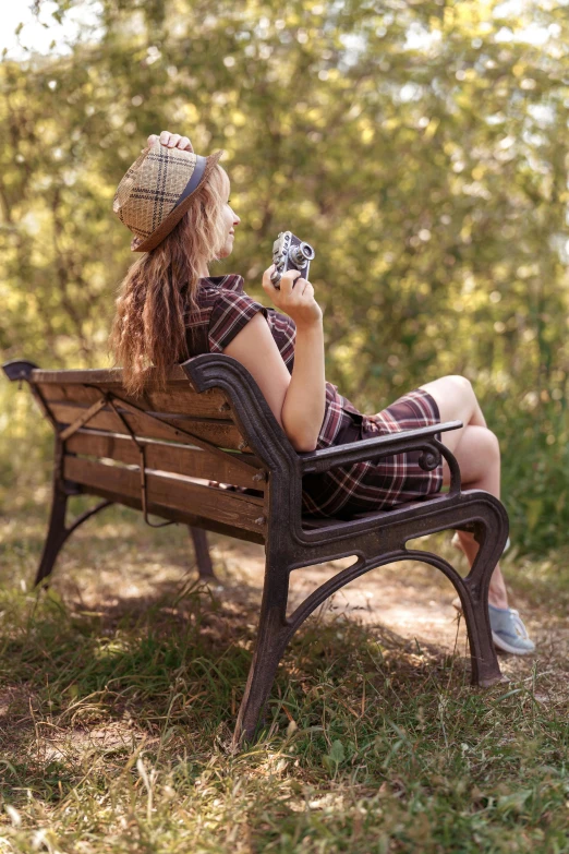 a woman sitting on a park bench holding a camera