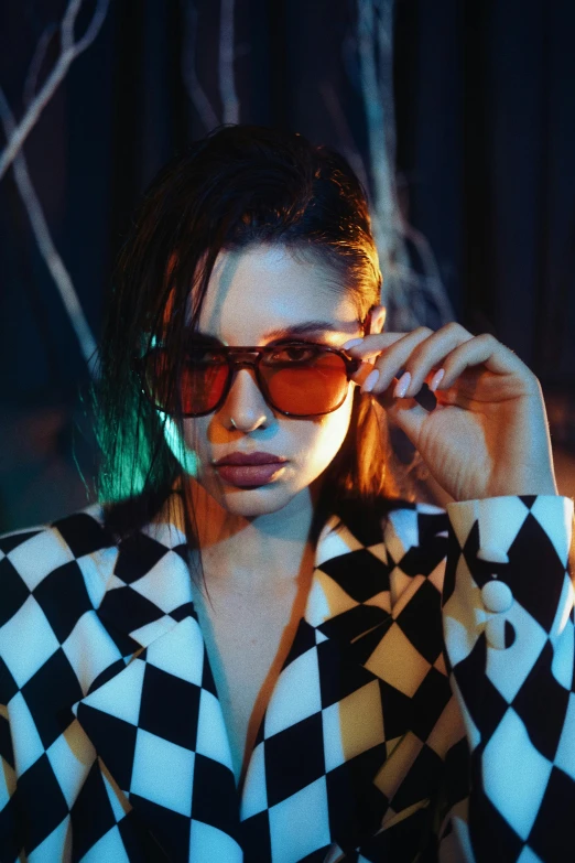 a woman wearing a checkered jacket and sunglasses