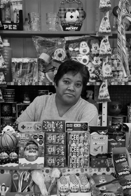 a woman sitting behind an assortment of various items in a store