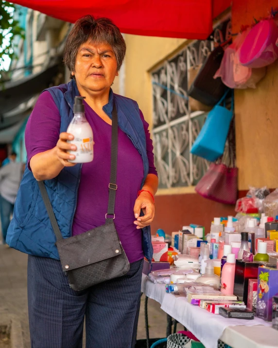 a woman holds a container of juice in front of a table with other objects