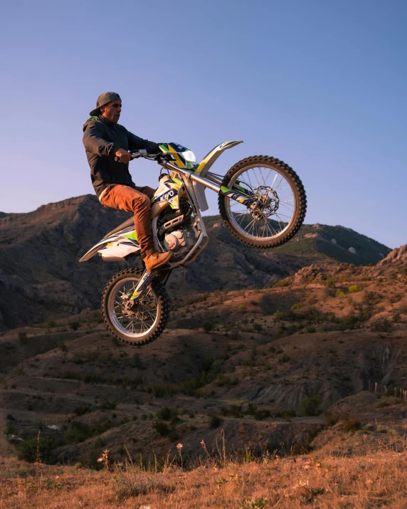 a person riding a motorcycle through the air on a mountain