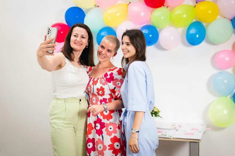 four women are taking a picture while posing in front of balloons