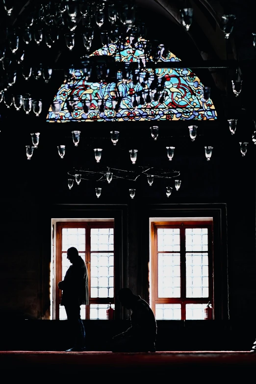 the silhouette of a person standing by two windows