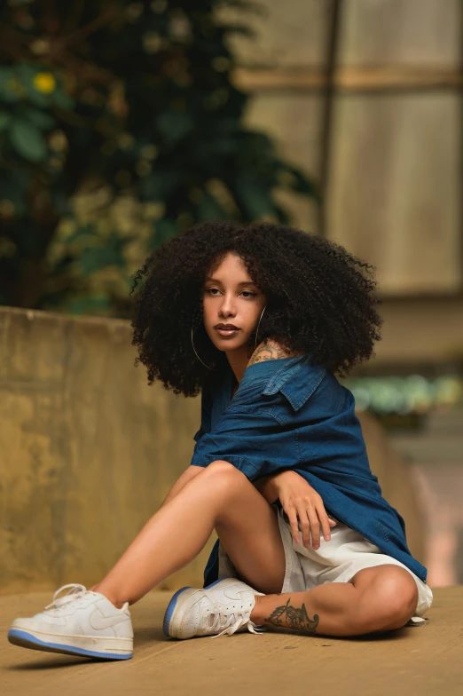 young woman with afro sitting on floor and leaning forward