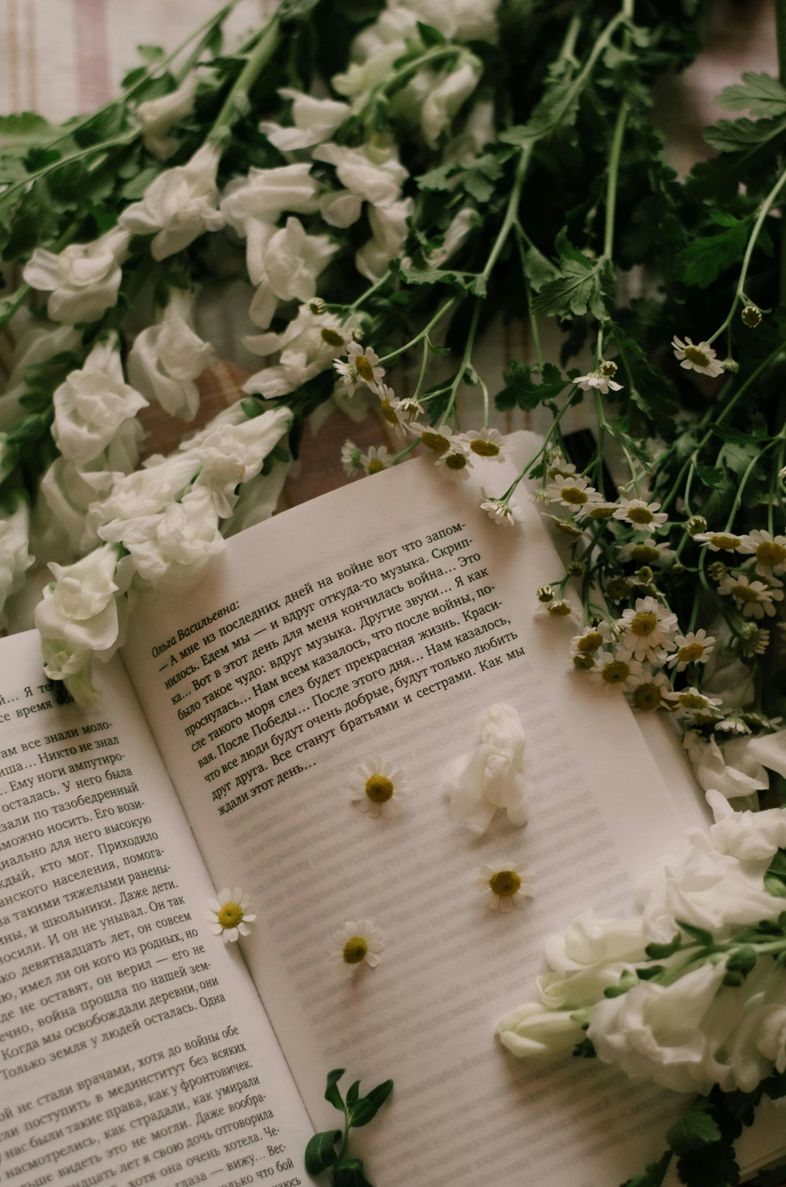 an open book with flowers next to it on the ground