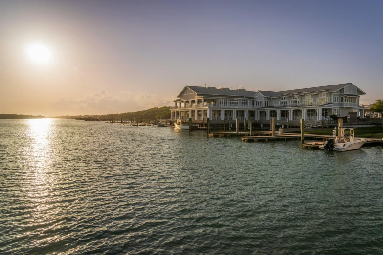 an old style house on the ocean with boats and docks