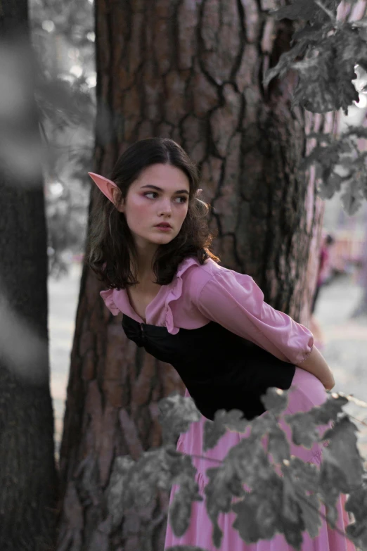 a woman wearing a costume leaning against a tree