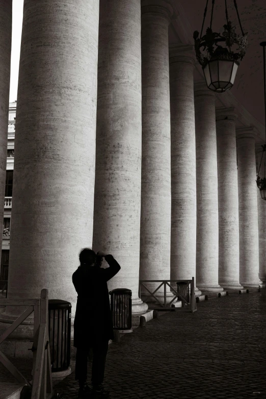 a man that is standing near some very tall pillars