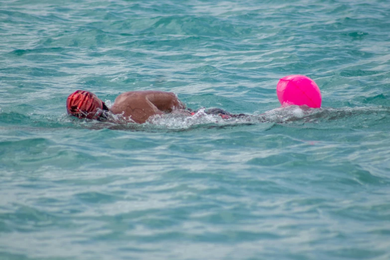 a woman swimming on top of the ocean with a red object in her hand