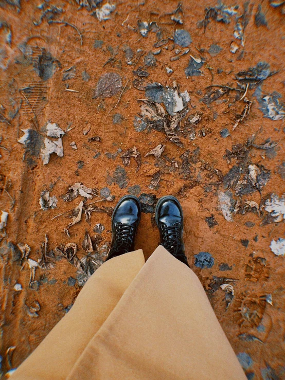 a person with dark black shoes stands on an orange ground