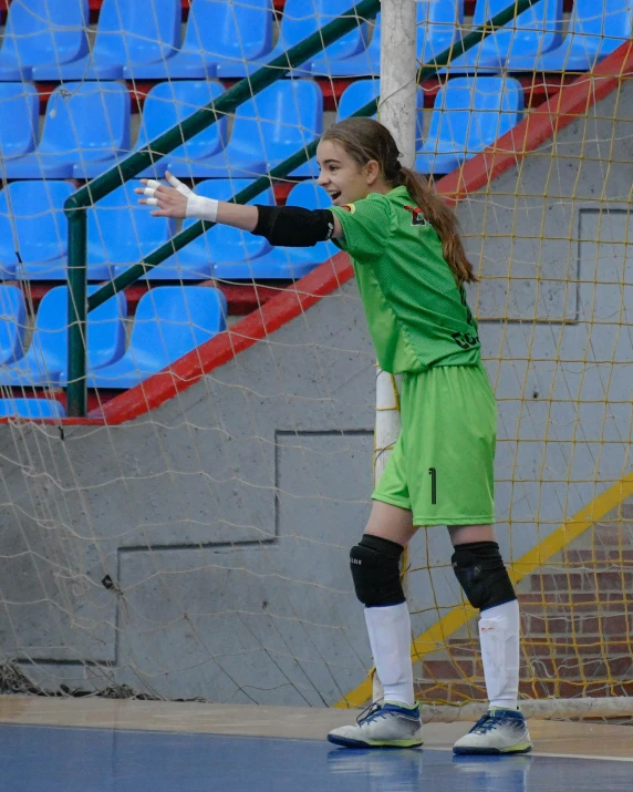 a girl with a green uniform getting ready to kick the ball