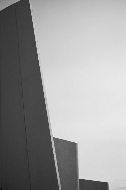 black and white image of a plane flying over the top of a tall building