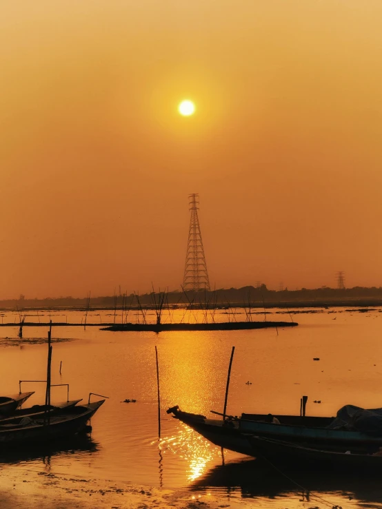 several boats anchored in the water as the sun sets