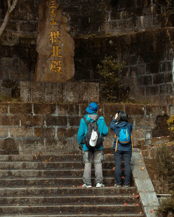 two people standing on top of stairs next to trees