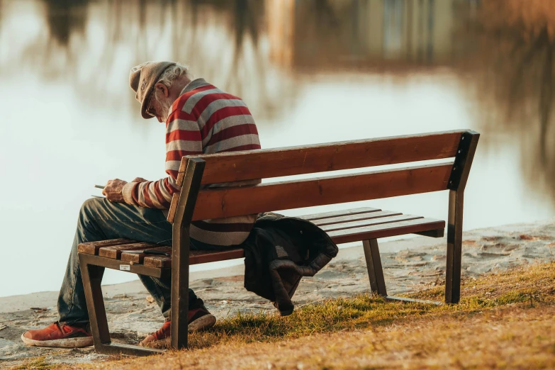 an old man sitting on a bench with his dog beside him