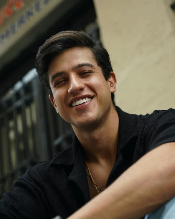 a smiling man with his arm around the back of a chair