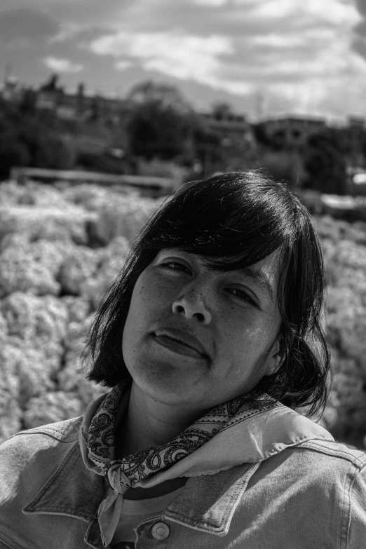 black and white po of woman standing near wall of grass