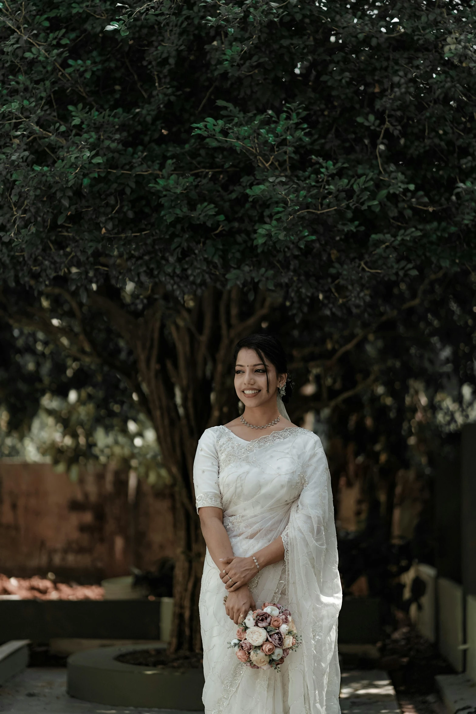 woman in white outfit standing on street with tree