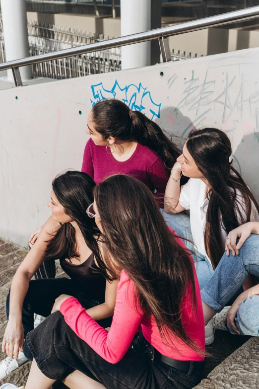 a group of young women are sitting next to a wall