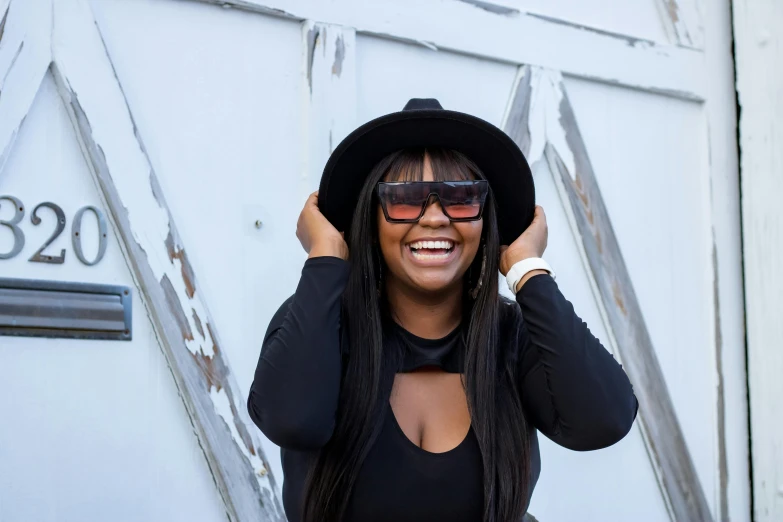 a woman wearing a black top and a black hat