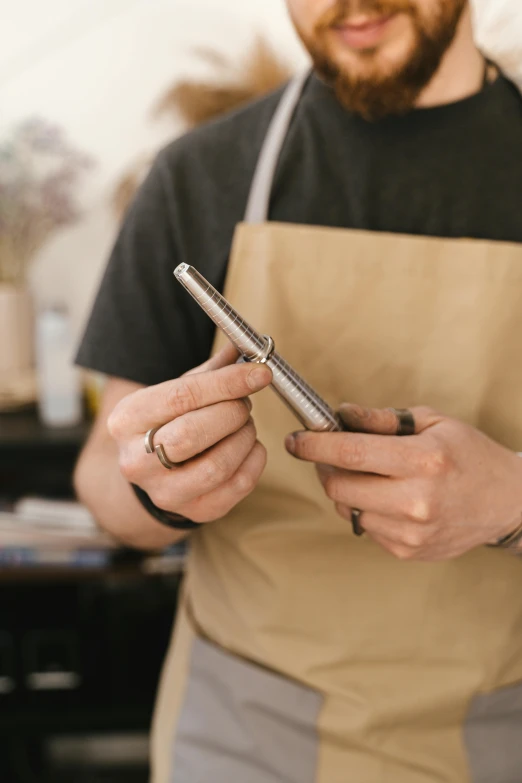 a man looking at his phone while wearing an apron