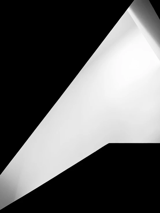 a triangular, mostly white sculpture with a light at the top