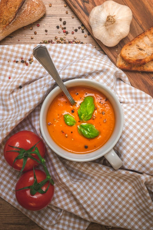 bowl of tomato soup next to a few sliced of bread