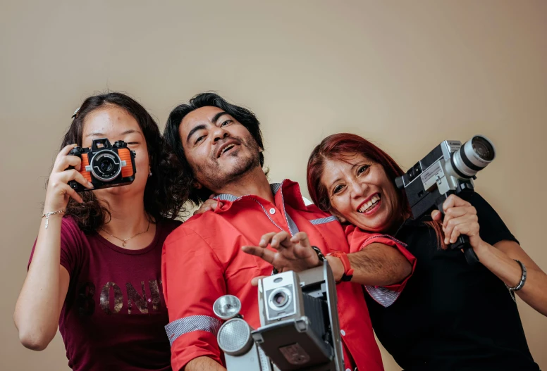 three people are holding cameras and posing for a picture