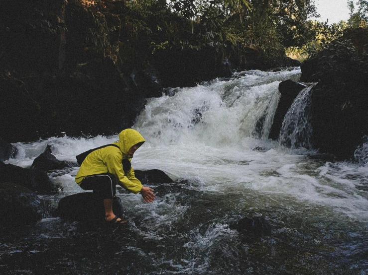 a person in yellow jacket standing at a river