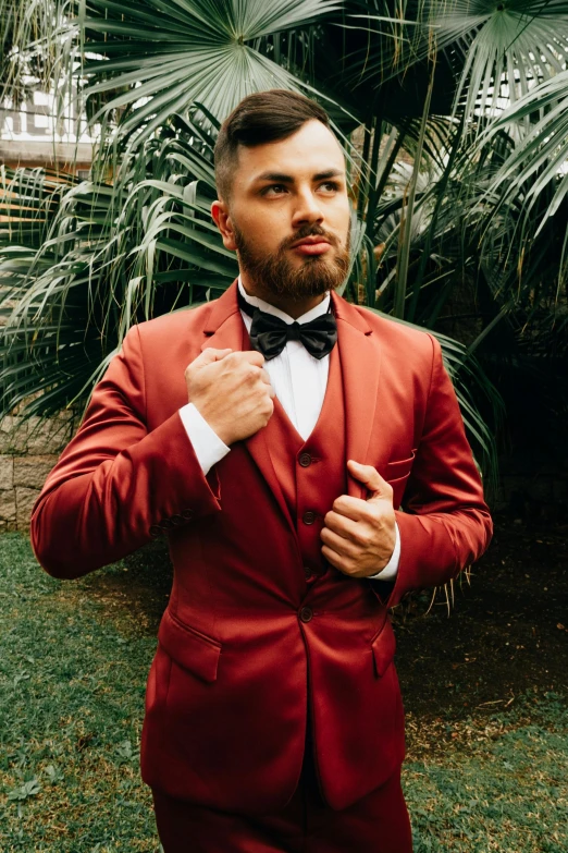 a man standing in the grass with his suit on