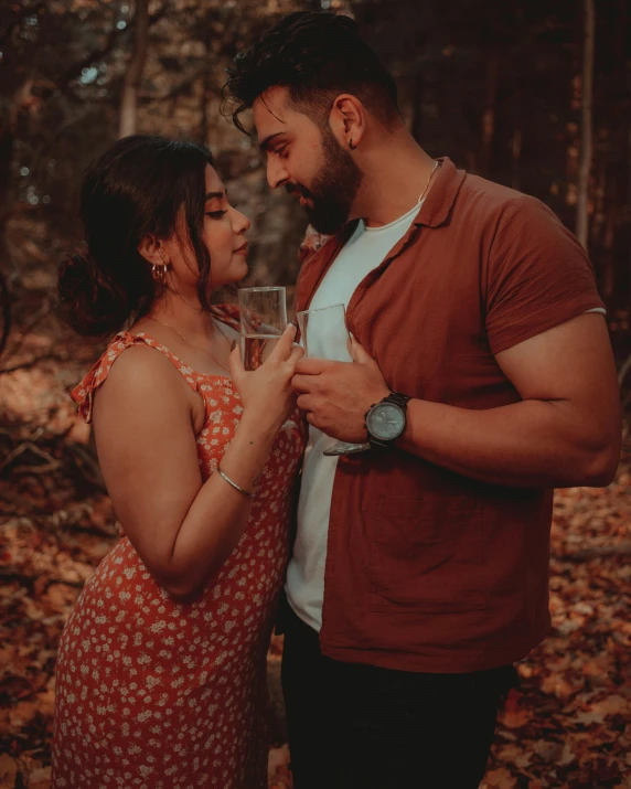 an image of a man and woman sharing a toast in the forest