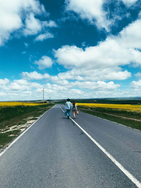 two people walk down the road on the opposite side