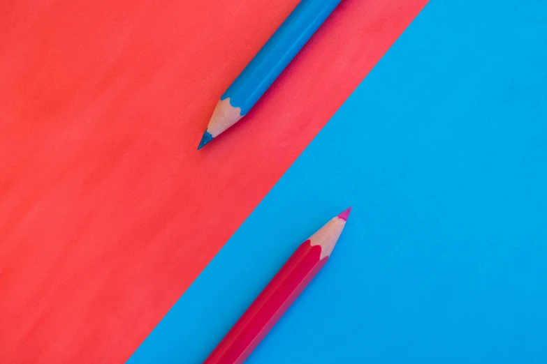 the colored pencils on the blue and red table