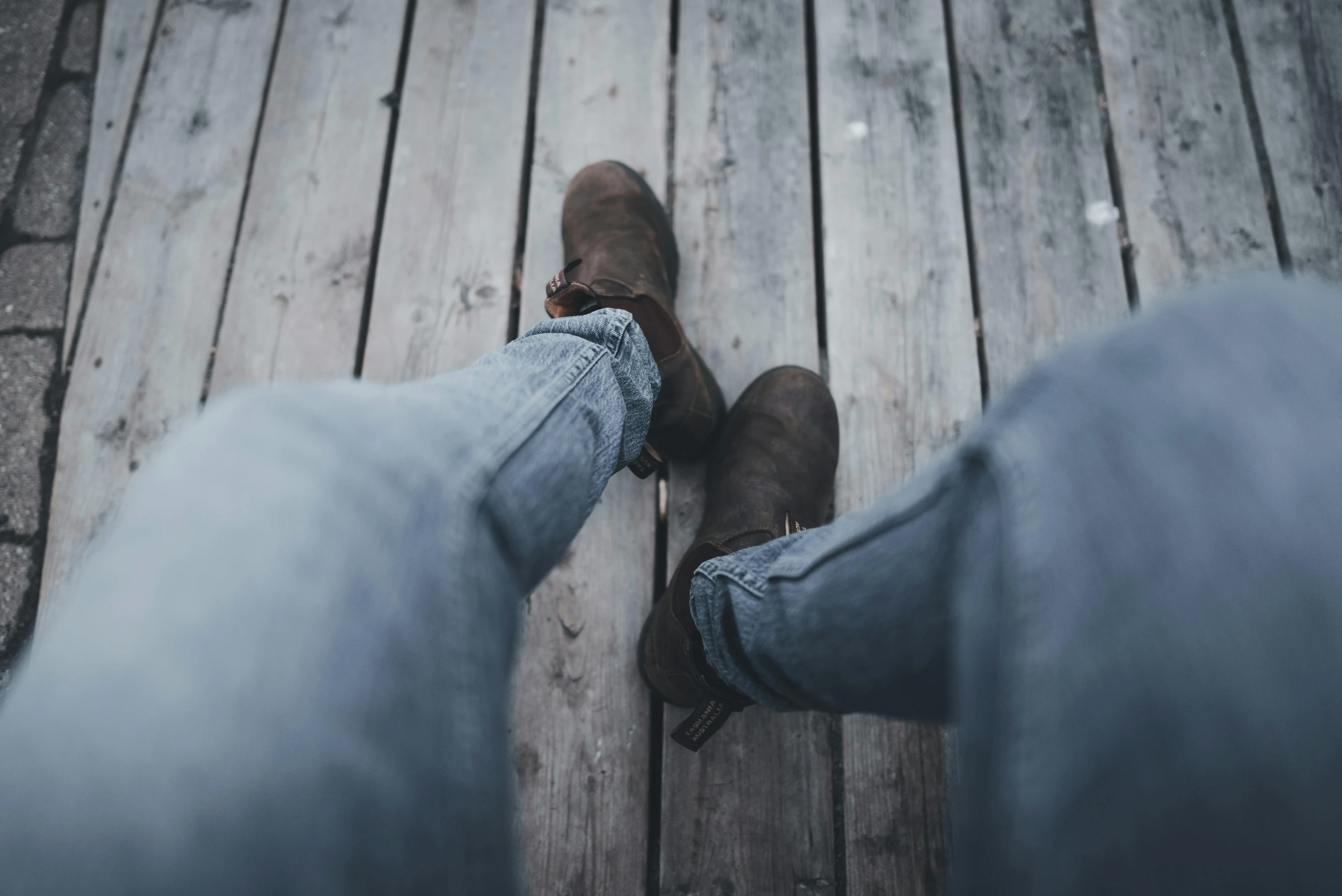 legs of two people standing on a wooden bridge