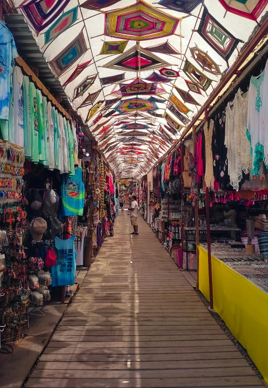 the inside of an indoor market with the bright colored umbrellas and the colorful cloth covering