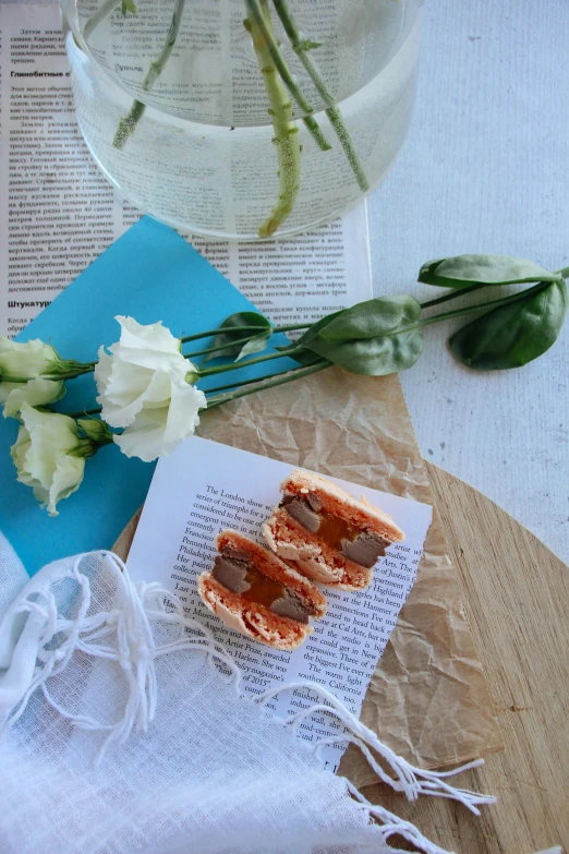 a flower sits on top of a book next to a glass of water