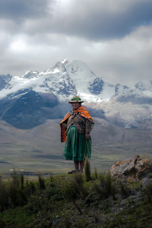 a person with an orange and green blanket standing on top of a mountain