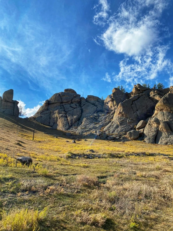 a grassy, arid landscape is seen under a partly cloudy sky