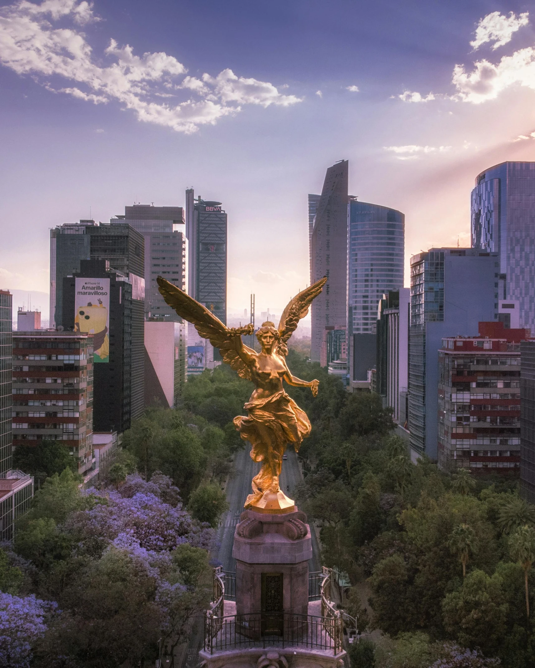 the large golden statue is in front of the city skyline