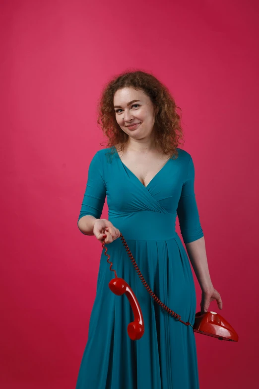 a woman in a blue dress holding a red purse and a telephone