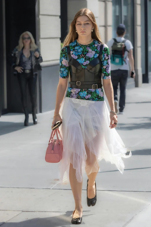a woman in a tulle skirt and top is walking on the sidewalk