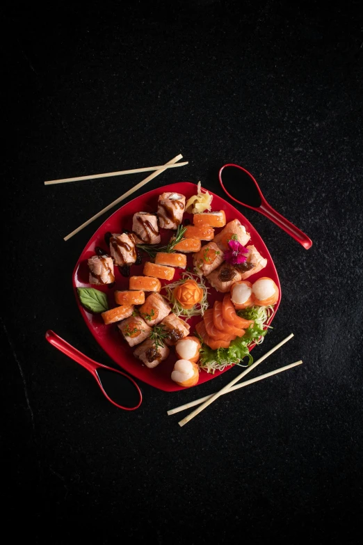 assorted sushi rolls on a red plate with chopsticks