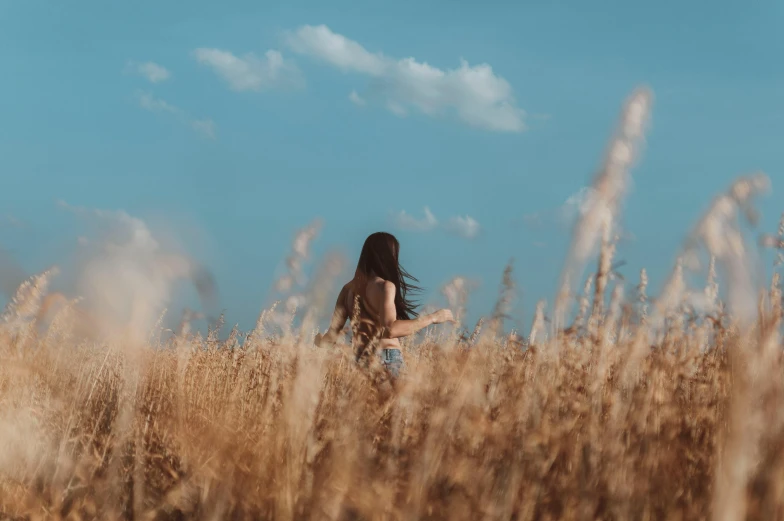 a woman standing in tall grass with her arms outstretched