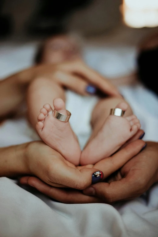 two people holding their hands over a newborn baby's foot