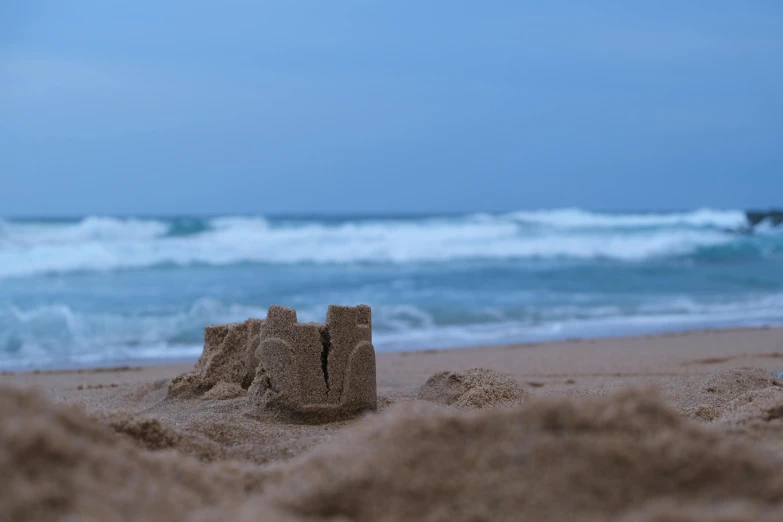 an unfinished sand castle sits on the beach