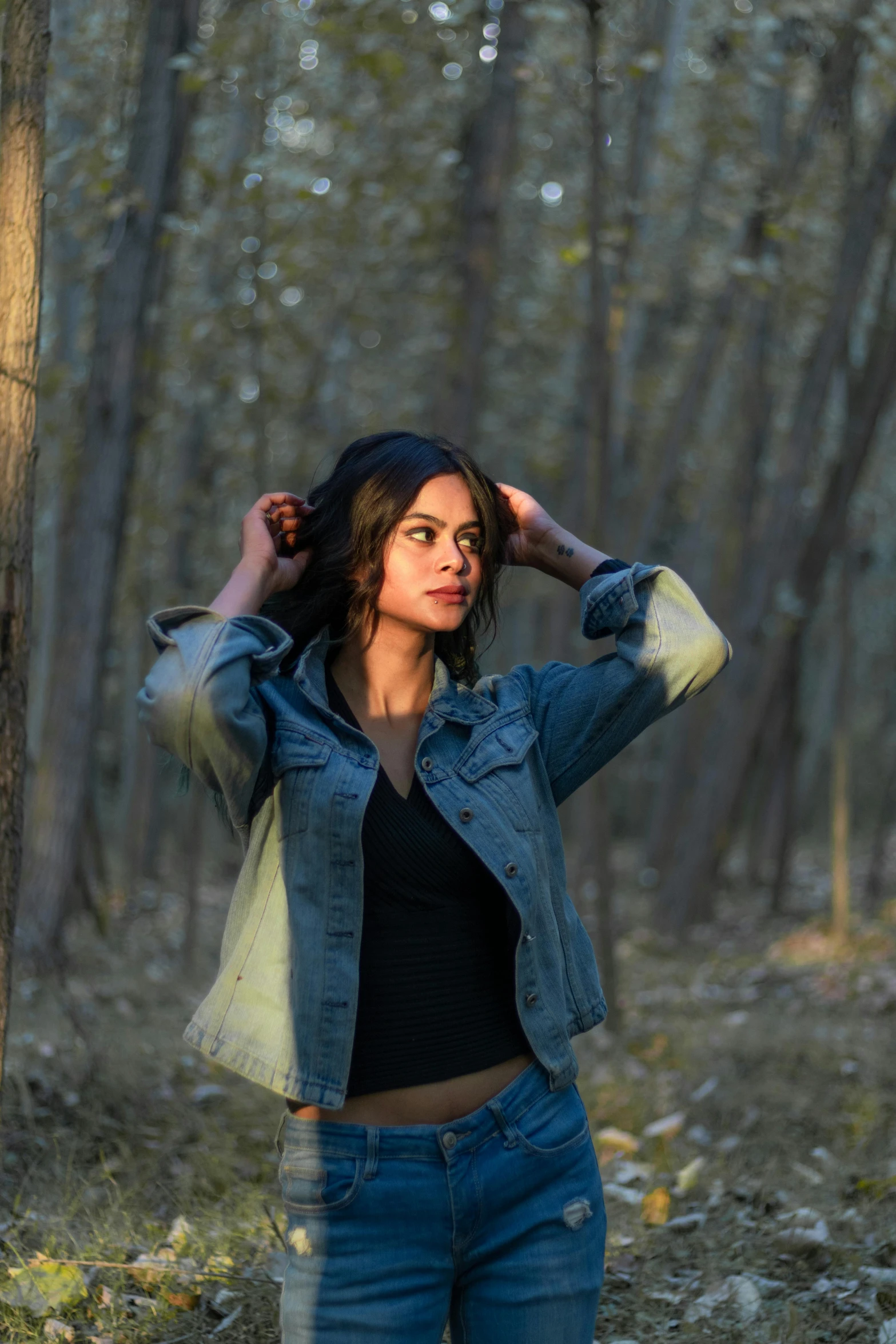 a woman stands in the woods near a tree