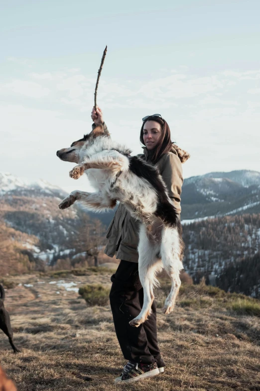 a man holding up a dog on a mountain