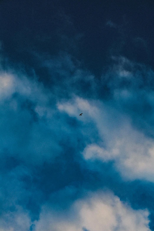 a plane flying in the sky under some clouds