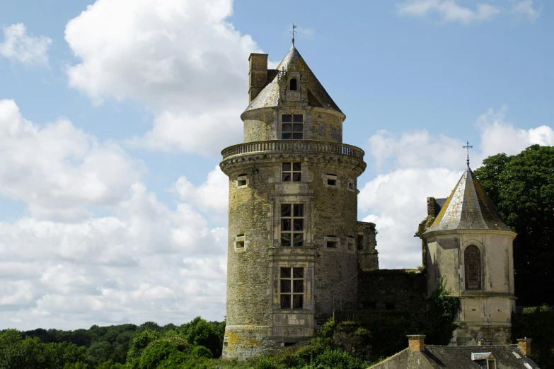 an old building stands amid greenery under a blue cloudy sky